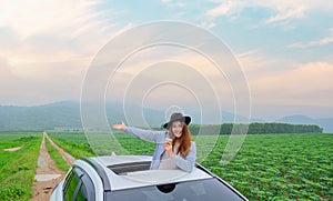 Asian woman standing out of car sunroof. Relaxing and freedom with spring time. Young tourist travel alone in Thailand