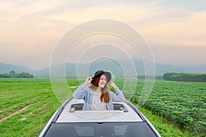 Asian woman standing out of car sunroof. Relaxing and freedom with spring time. Young tourist travel alone in Thailand