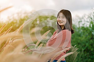 Asian woman Standing smiling in the fields of brown grass in the morning sun With a happy face