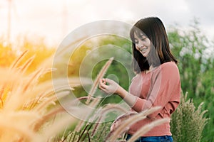 Asian woman Standing smiling in the fields of brown grass in the morning sun With a happy face