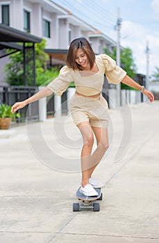 Asian woman standing on Surfskate Background of streets and houses