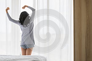 Asian woman stretch lazily in bedroom