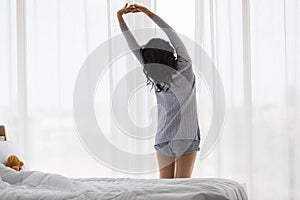 Asian woman stretch lazily in bedroom