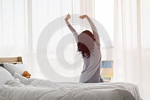 Asian woman stretch lazily in bedroom