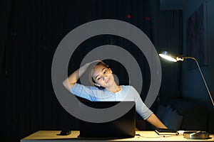 Asian woman are stretch lazily while working long hours in front of a computer in late night in living room at home