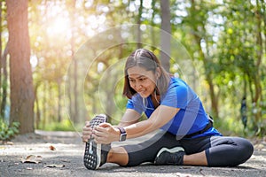 Asian woman stretch muscles at park and listening to music