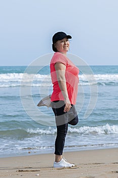 An asian woman stretching on the beach