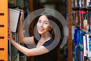 Asian woman student read text book in her university library