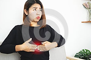Asian woman suffering from Epigastric pain caused by acid indigestion, GERD in a stomach