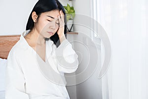 Asian woman suffering from headache, dizziness after wakeup in morning hand holding her head