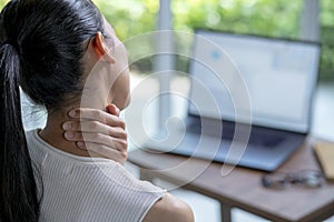 Asian woman suffering from neck pain in home office