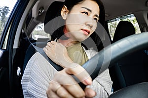 Asian woman suffering from neck and shoulder pain while driving behind the wheel of car ,