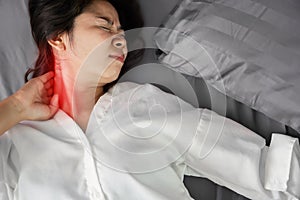 Asian woman suffering from neck sprain or a crick in her neck during sleeping in the bed