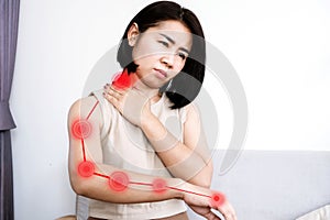 Asian woman suffering from nerve and muscle pain in neck and shoulder radiating down arm photo