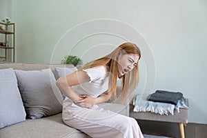 asian woman suffering from stomach ache, undergoing belly pain and discomfort, suffer from menstruation