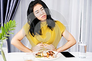 Asian woman suffering from stomachache, GERD after eating spicy food hand holding her pain stomach photo