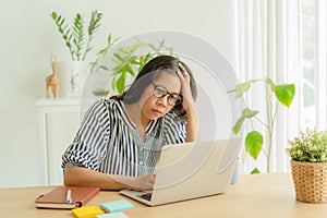 Asian woman suffering stress working on laptop in overwork. Tired businesswomen using a computer.