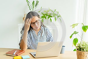 Asian woman suffering stress working on laptop in overwork. Tired businesswomen using a computer.  She use her hand to touch her