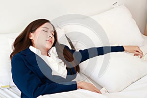 Asian woman in a suit lying on the bed. Female employees work overtime.
