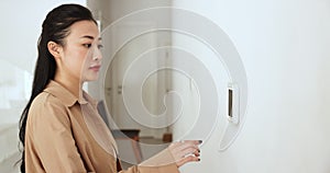 Asian woman switches on alarm, burglar protection or climate control