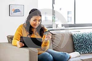 Asian woman with tablet pc and credit card at home