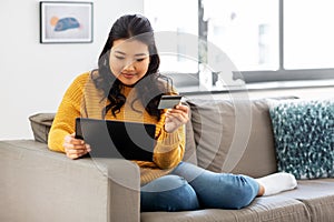 Asian woman with tablet pc and credit card at home