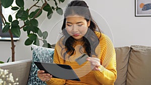 Asian woman with tablet pc and credit card at home