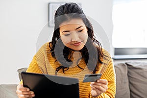 Asian woman with tablet pc and credit card at home