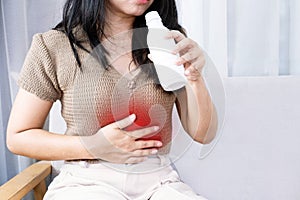 Asian woman taking antacid medicine gel to treat her heartburn from gerd and stomachache