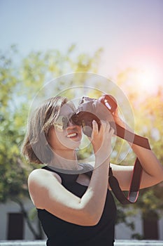 asian woman taking a photo with dslr camera standing outdoor against beautiful sun light