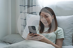 Asian woman taking selfie or making video call on smart phone on the bed