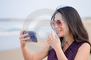 Asian woman taking selfie with mobile phone - lifestyle photo of young happy and beautiful Korean girl taking self portrait on