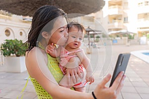 Asian woman taking selfie photo with her adorable baby girl - beautiful Chinese mother holding her little daughter and taking