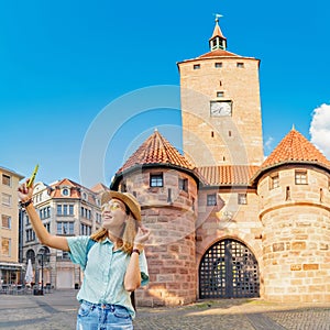 Asian woman taking selfie photo at the Tourist attraction the White Tower in Nuremberg old town