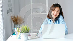 Asian woman talking phone while working with laptop computer at home office, Asia female girl work from home, telecommunication