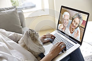 Asian woman talking with senior parents via video chat using laptop computer