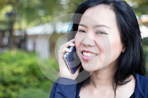 Asian woman talking on smart phone at park. Communication concept. Extrovert characteristic. chit chat with friend photo