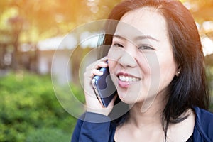 Asian woman talking on smart phone at park. with sunlight effect. Communication concept. Extrovert characteristic. chit chat with photo