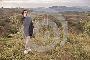 An asian woman talks to a friend on her cellphone while trekking through the beautiful countryside. Exercise and leisure concept