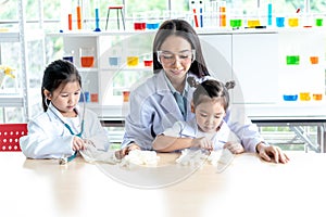 Asian woman teacher And 2 girl student, wearing a white doctor uniform, learning  the science  in classroom