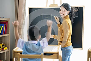 Asian woman teacher and her smart student in class room with backboard background