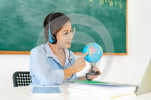 Asian woman teacher teaching geography via video conference e-learning in laptop with blackboard at classroom. Homeschooling and