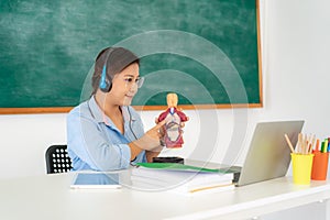 Asian woman teacher teaching physiology via video conference e-learning in laptop with blackboard at classroom. Homeschooling and