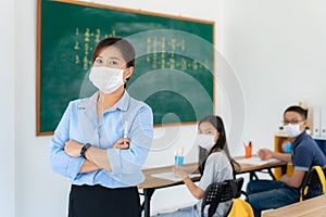 Asian woman teacher wearing masks to prevent the outbreak of Covid 19 in classroom with student while back to school reopen their