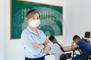 Asian woman teacher wearing masks to prevent the outbreak of Covid 19 in classroom with student while back to school reopen their photo