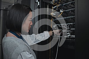 Asian woman, technician and server room for cabling, networking or system maintenance at office. Female engineer