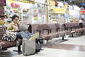Asian woman teenager using smartphone at airport terminal sittin