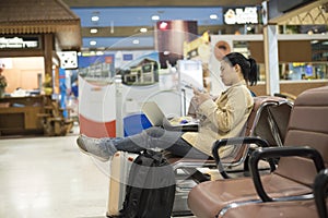 Asian woman teenager using smartphone and laptop at airport term