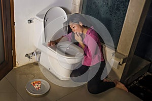 Asian woman throwing up forcing with fingers for vomiting pizza feeling guilty worried about getting fat in bulimia nutrition