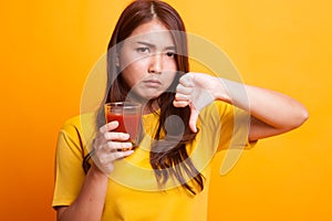 Asian woman thumbs down hate tomato juice in yellow dress